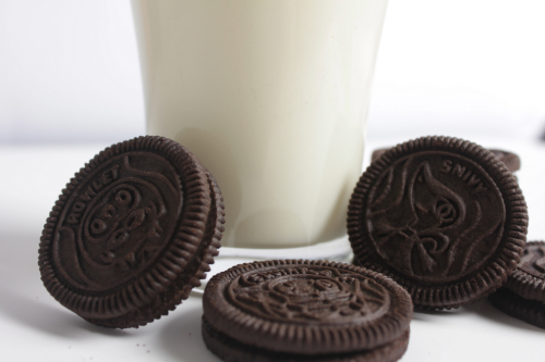 a close up picture of oreo cookies leaning on a glass of milk